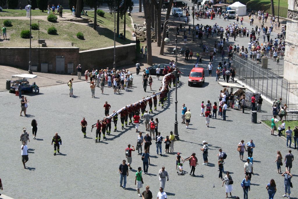 A bunch of firemen carrying a large canopy up to the Colosseum